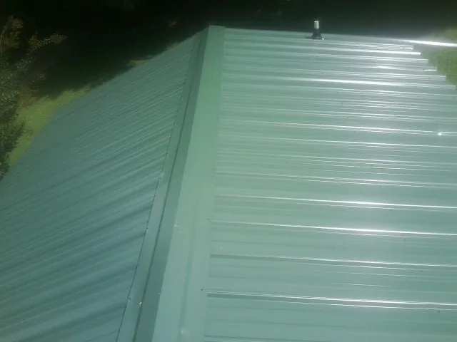 New green metal panels meeting at the ridge of a roof — Flat Roof Repair work by our crew in Bridgeport